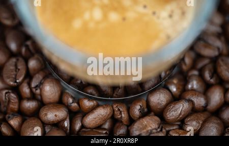 Detail einer Tasse Kaffee auf den Kaffeebohnen. Selektiver Fokus. Abstrakte Illustration. Brauner Hintergrund. Stockfoto