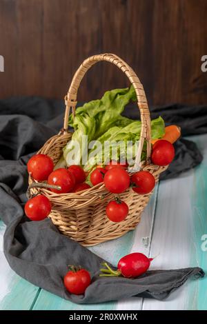 Ein Korb aus Korb enthält rote Kirschtomaten, Salat und Karotten Stockfoto