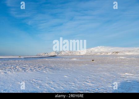 Blick über die schneebedeckte flache vulkanische Landschaft mit Bergen im Hintergrund in der Nähe des Eyjafjallajokull-Gletschers und Vulkans im südlichen Islands Agai Stockfoto