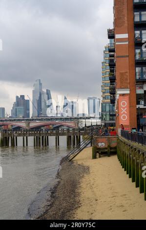 LONDON - 21. April 2023: Machen Sie einen Spaziergang am Sandstrand der Themse und genießen Sie den Blick auf die OXO Tower Wharf und die Skyline von London in der Distan Stockfoto