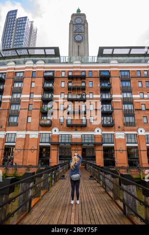 LONDON - 21. April 2023: Eine Fotografin fotografiert die OXO Tower Wharf von einem Holzsteg an der Themse aus. Stockfoto