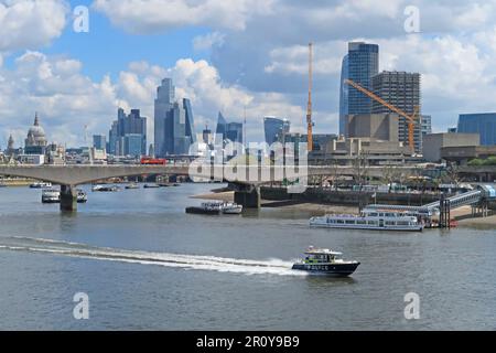 London, Großbritannien. Eine Polizeischleuder rast auf der Themse. Waterloo Bridge und die Türme der Stadt London dahinter. Mai 2023. Stockfoto