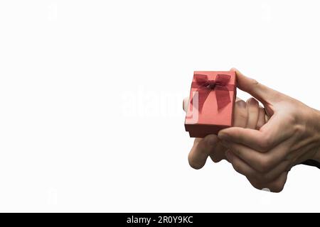 Nahaufnahme einer Person, die ein Geschenk auf weißem Hintergrund hält. Antrag oder Geburtstagsgeschenk. Stockfoto