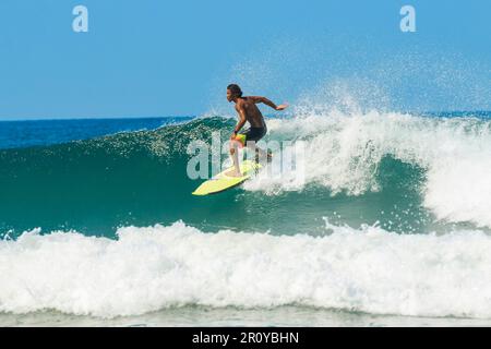 Surfen Sie auf dem Wappen einer brechenden Welle an diesem schnell wachsenden Surfstrand und Yoga-Ziel. Playa Guiones, Nosara, Guanacaste, Costa Rica Stockfoto