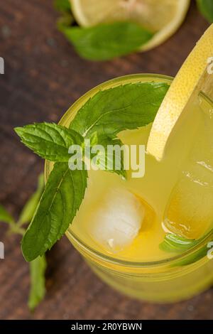 Limonade mit frischen Minzeblättern und Zitronenscheibe in Glas auf einem Holztisch Stockfoto