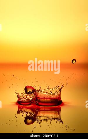 Spritzer Wasser auf einem roten und gelben Hintergrund Stockfoto