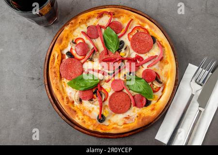 Gemischte Pizza mit Wurst, Salami und Pilzen auf einem Steintisch Stockfoto