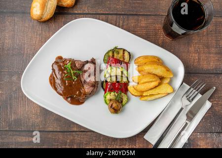 Gegrilltes Rinderfilet mit Demi-Glace-Sauce mit gegrilltem Gemüse auf einem weißen Porzellanteller Stockfoto