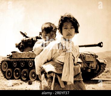 Mit ihrem Bruder auf dem Rücken stapft ein Krieg müde koreanisches Mädchen müde durch einen ins Stocken geratenen M-26 Tank, Haengju, Korea.  9. Juni 1951.  Foto von Generalmajor R.V. Spencer, UAF. (Marine) Stockfoto