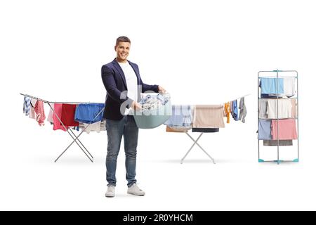 Das Porträt eines jungen Mannes in voller Länge, der einen Wäschekorb vor Wäscheleinen hält, isoliert auf weißem Hintergrund Stockfoto