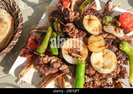 Blick von oben köstliches gemischtes Kebab Fleisch Chopsteak Fleischklößchen Spiewer Lamm mit Gemüse Pfeffer Tomaten Zwiebeln in der Nähe des Brots. Stockfoto