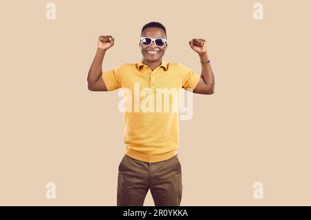 Ein junger afroamerikanischer Mann lächelt und demonstriert Kraft mit muskulösen Armen im Studio Stockfoto