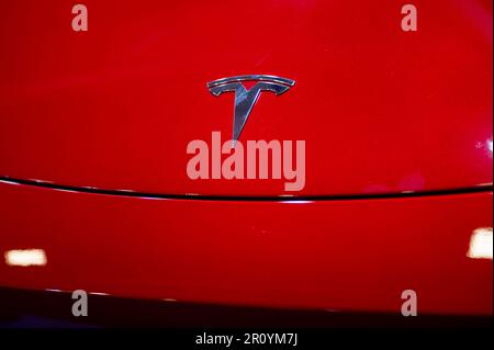 Riga, Lettland, 28. April 2023: Nahaufnahme verchromter Llgotype Tesla Motors auf roter Haube Stockfoto