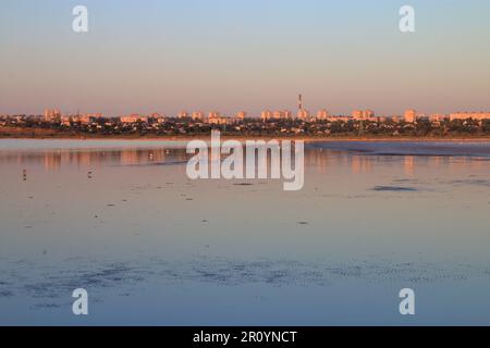 Das Foto wurde an der Mündung von Kuyalnitsky in der Stadt Odessa aufgenommen. Auf dem Foto die Silhouette der Stadt in den Strahlen der untergehenden Sonne. Stockfoto