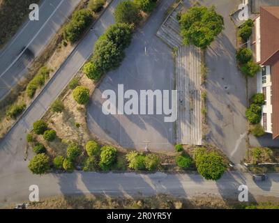 Luftaufnahme eines weitläufigen leeren Stadtparkplatzes mit Parkplatzreihen und einer gewundenen Straße, die vom Parkplatz weg führt Stockfoto