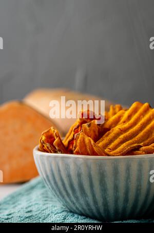 Süßkartoffelchips in einer Schüssel. Süßkartoffeln im Hintergrund. Stockfoto