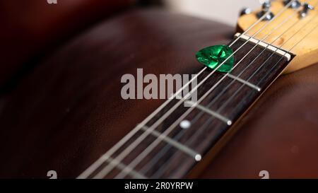 Green Guitar Pick in Guitar Streicher Stockfoto