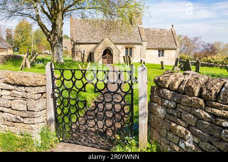 Kirche St. James im Dorf Clapton-on-on-the-Hill in Cotswold, Gloucestershire, Vereinigtes Königreich. Das schmiedeeiserne Hufeisen-Tor wurde von Raymond Phillips hergestellt. Stockfoto