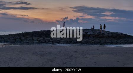 Pantai Jerman (deutscher Strand) in Kuta, Bali Indonesien bei Sonnenuntergang, bei dem die Leute den Strand genießen Stockfoto