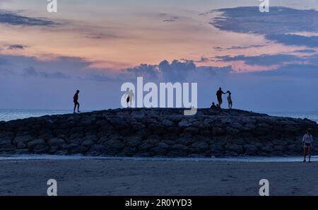 Pantai Jerman (deutscher Strand) in Kuta, Bali Indonesien bei Sonnenuntergang, bei dem die Leute den Strand genießen Stockfoto