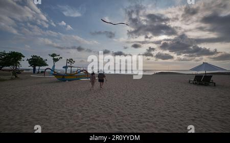 Pantai Jerman (deutscher Strand) in Kuta, Bali Indonesien, Sonnenuntergangsaufnahme, bei der Boote im Ozean gezeigt werden, während Menschen den Strand genießen Stockfoto