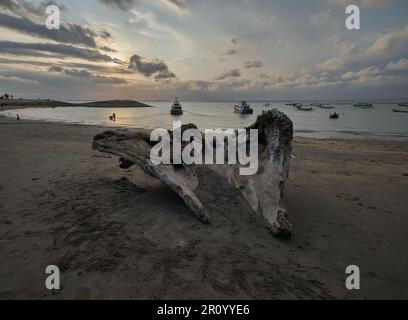 Pantai Jerman (deutscher Strand) in Kuta, Bali Indonesien, Sonnenuntergangsaufnahme, bei der Boote im Ozean gezeigt werden, während Menschen den Strand genießen Stockfoto