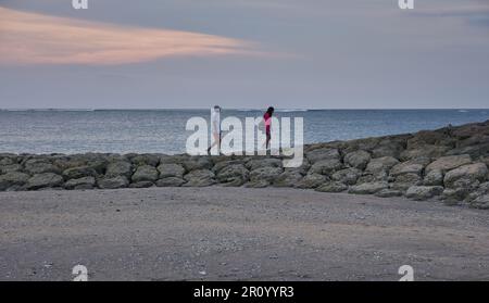 Pantai Jerman (deutscher Strand) in Kuta, Bali Indonesien bei Sonnenuntergang, bei dem die Leute den Strand genießen Stockfoto