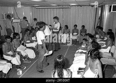 Vietnamesische Flüchtlinge werden untersucht und an Bord der USS BLUE RIDGE (LCC 19) verarbeitet. Die 35 refugeees wurden gerettet durch den amphibischen Kommando Schiff 350 Meilen nordöstlich von Cam Ranh Bay, Vietnam, nach acht Tage auf See in einem 35-Fuß-Boot. Stockfoto