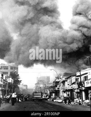 Schwarzer Rauch bedeckt Bereiche von Saigon, während Feuerwehrautos zu den Schauplätzen von Bränden eilen, die während der Tet-Feiertage von den Vietcong angegriffen wurden. Ungefähr 1968. Stockfoto