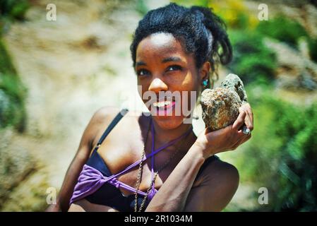 Wunderschöne schwarze Frau in lila Kleidung, gestrandet auf einer einsamen Insel Stockfoto