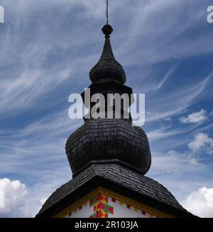 Eine alte Kirche mit einem spitzen hohen Turm und einem Holzdach am Bohinjsee in Slowenien. Stockfoto