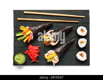 Bambusmatte mit leckeren Sushi-Zapfen, Ingwer und Wasabi auf weißem Hintergrund Stockfoto