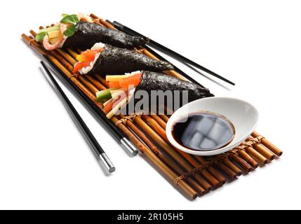 Bambusmatte mit leckeren Sushi-Zapfen, Sojasoße und Essstäbchen auf weißem Hintergrund Stockfoto