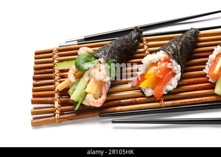 Bambusmatte mit leckeren Sushi-Zapfen und Essstäbchen auf weißem Hintergrund, Nahaufnahme Stockfoto