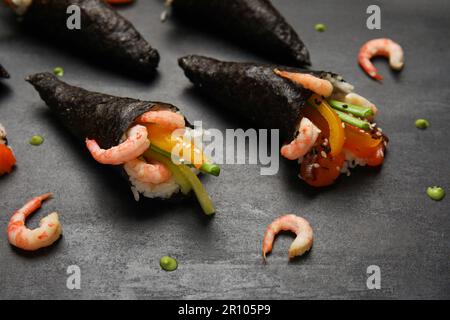 Leckere Sushi-Zapfen, Garnelen und Wasabi-Tropfen auf dunklem Hintergrund, Nahaufnahme Stockfoto