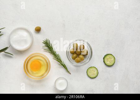 Zusammensetzung mit Gläsern aus Creme und natürlichen Zutaten auf hellem Hintergrund Stockfoto