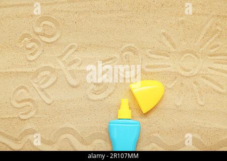 Kreative Komposition mit Sonnencreme und Zeichnungen auf Sand Stockfoto