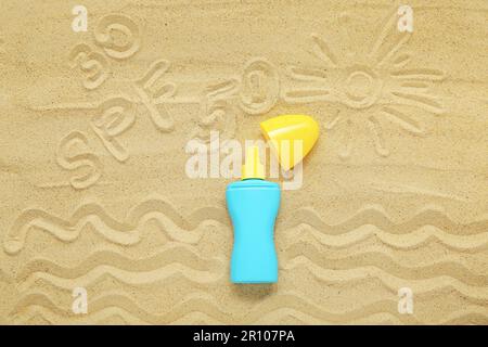 Kreative Komposition mit Sonnencreme und Zeichnungen auf Sand Stockfoto