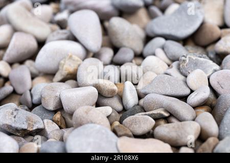 Nahaufnahme von runden Kieselsteinen am Strand. Grauer Steinhintergrund, selektiver Fokus Stockfoto