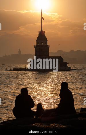 Bei einem sonnigen Sonnenuntergang beobachten die Menschen den Jungfrauenturm und den Galataturm über den Felsen. Stockfoto