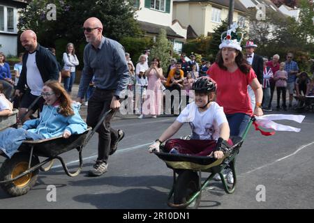 Familien, die am Wheelbarrow Race bei der Street Party teilnehmen, um König Charles III. Krönung Surrey England zu feiern Stockfoto