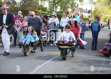 Familien, die am Wheelbarrow Race bei der Street Party teilnehmen, um König Charles III. Krönung Surrey England zu feiern Stockfoto