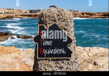 FTE-Symbol für Vollzeitäquivalent. Konzeptwörter FTE Vollzeitäquivalent auf wunderschöner schwarzer Kreidetafel. Wunderschöner Steinstrand im Hintergrund. Geschäfte Stockfoto