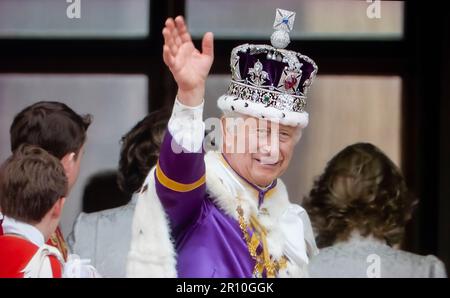 König Karl III. Winkt vom Balcony Buckingham Palace, trägt die Krone des Staates (die kaiserliche Staatskrone) und seine Krönungsgarderobe, winkt ein Dankeschön an die Menschenmassen unten, vom Balkon des Buckingham Palace, nach der Krönung von ihm und Königin Camilla in Westminster Abbey Westminster London am 6. 2023. Mai Stockfoto