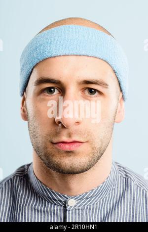 Nur glückliche Menschen lächeln. Ein gutaussehender junger Mann, der allein im Studio steht und posiert, während er ein Stirnband trägt. Stockfoto