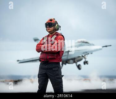 230508-N-XK462-1084 PHILIPPINE SEA (8. MAI 2023) USA Navy Aviation Ordnanceman 3. Class Juan Garcia aus Virginia Beach, Virginia, beobachtet den Flugbetrieb auf dem Cockpit des Flugzeugträgers USS Nimitz (CVN 68). Nimitz ist in der US-7.-Flotte und führt Routineeinsätze durch. 7. Fleet sind die USA Die größte Flotte der Navy, die mit einer Anzahl von Flotten ausgestattet ist, interagiert und arbeitet regelmäßig mit Verbündeten und Partnern zusammen, um eine freie und offene Region im Indo-Pazifik zu erhalten. (USA Marinebild von Mass Communication Specialist 3. Class Hannah Kantner) Stockfoto