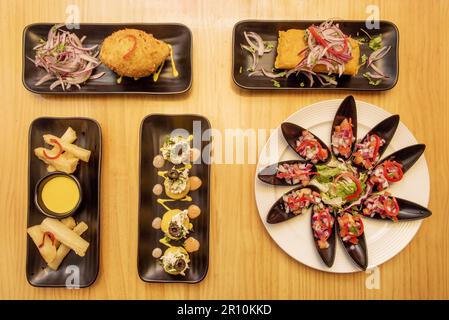 Ein Set köstlicher peruanischer Gerichte mit Muscheln mit Pico de gallo, gefüllter Tamale, gefüllter Kartoffel und gebratenen Yucca-Streifen Stockfoto