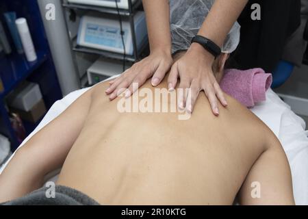 Anwendung einer Massage auf den Rücken eines Patienten in einem ästhetisch-medizinischen Zentrum Stockfoto