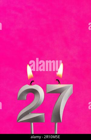 Kerze Nummer 27 - Geburtstagsfeier mit fuchsianischem Hintergrund Stockfoto