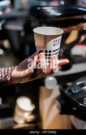 Elegante tätowierte Hand und Finger einer Damenhand, die eine Kaffeetasse hält Stockfoto